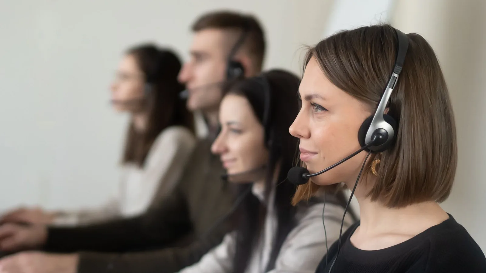 Czteroosobowy zespół obsługi telefonicznej ze słuchawkami przy komputerach